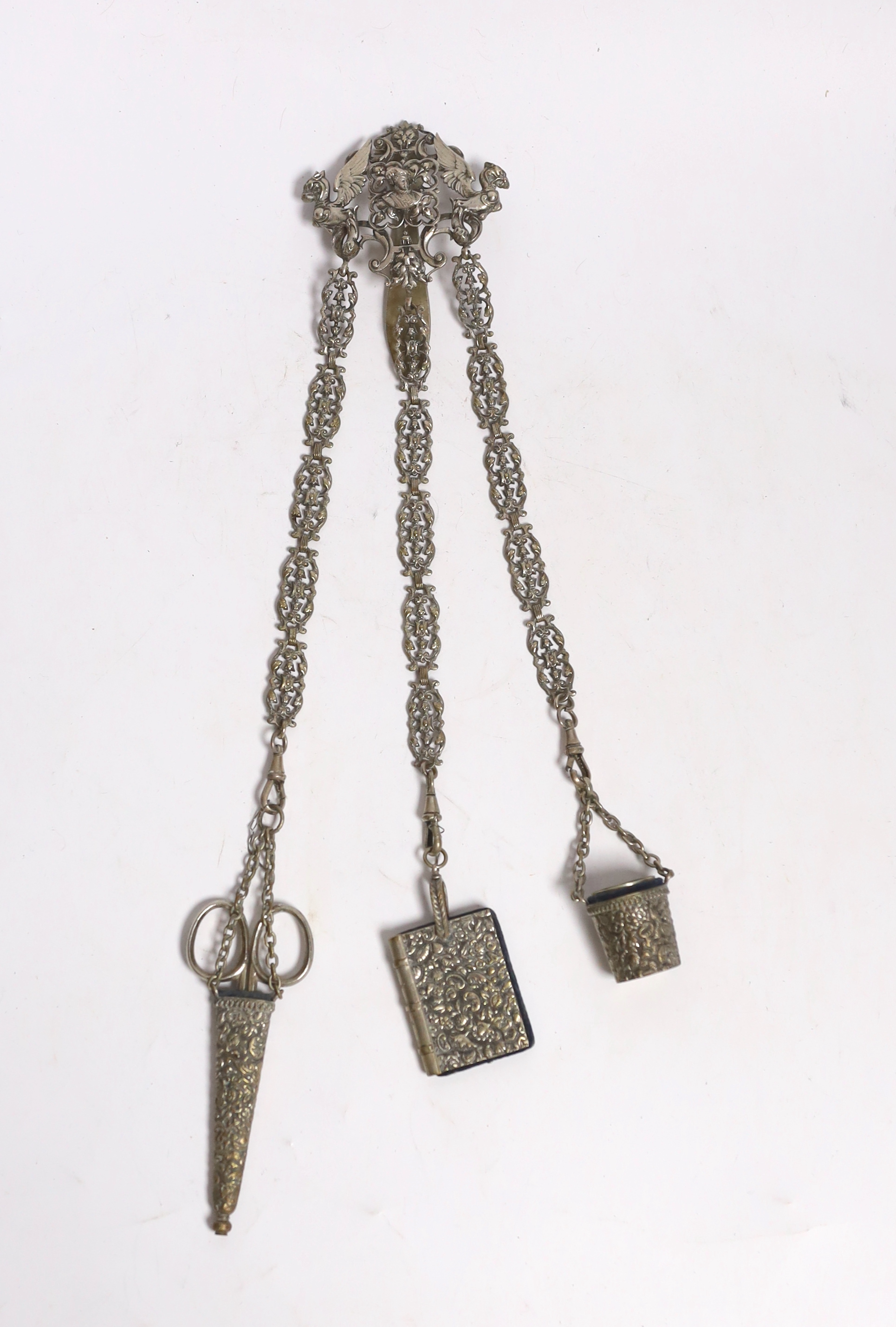 A late 19th century pierced silver plated chatelaine, hung with three accoutrements, to include a cased pair of scissors, pin cushion and thimble holder, overall 29.5cm.